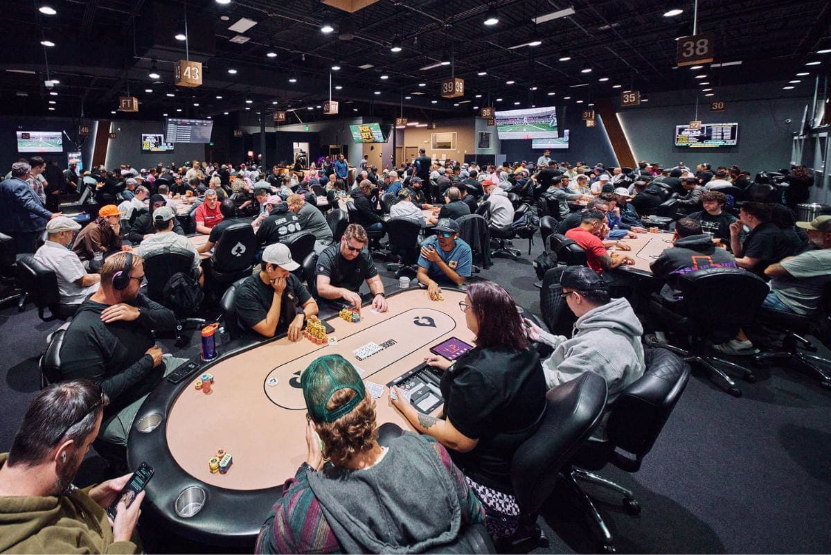 Duża sala turniejowa z wieloma graczami przy stołach pokerowych
